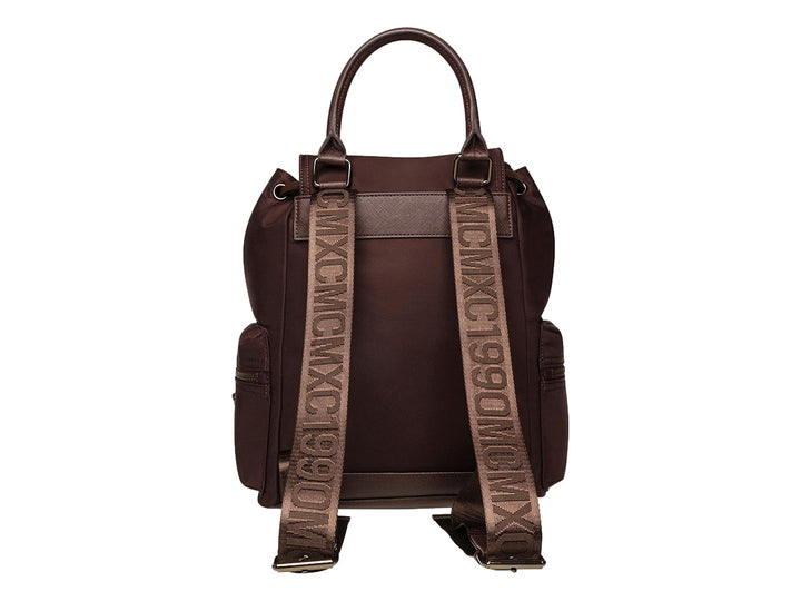Mochila Steve Madden color café con detalles en bronce, asa superior y bolsillos laterales.