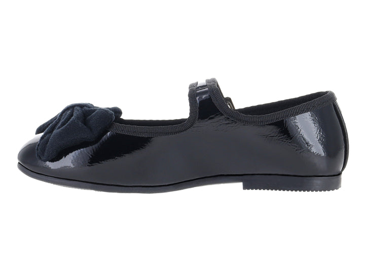 Zapato tipo ballerina negro de charol con moño y correa con hebilla plateada.