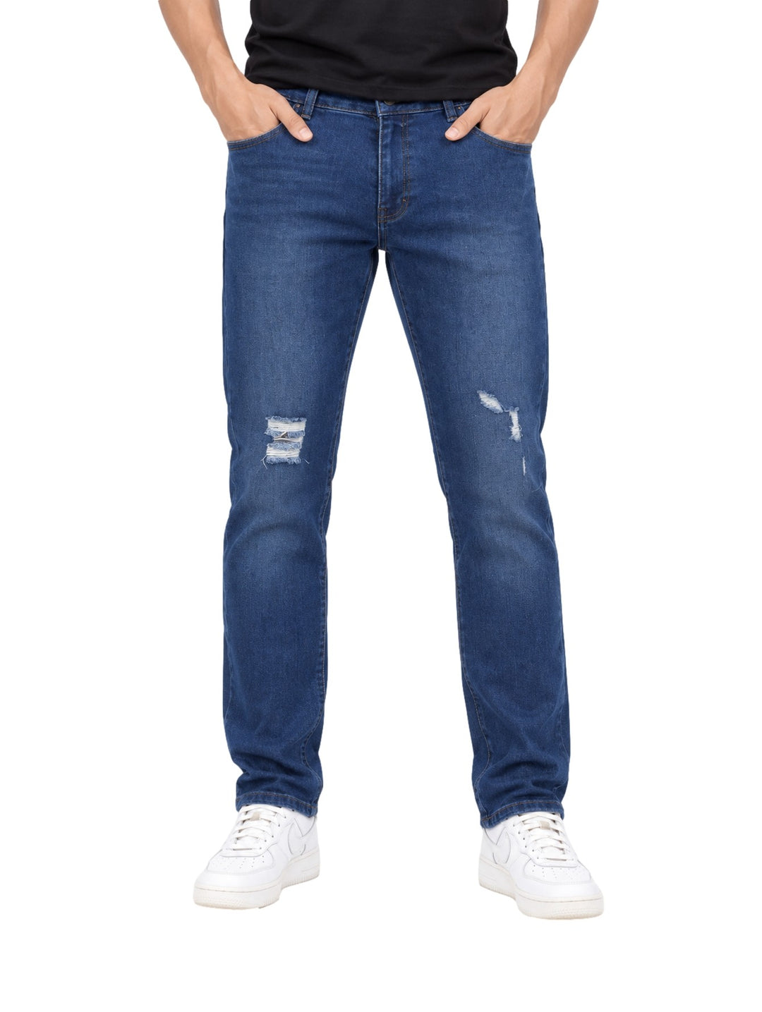 Hombre vistiendo jeans rectos color azul stone con detalles desgastados en las rodillas y tenis blancos.