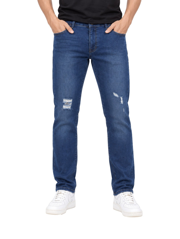 Hombre vistiendo jeans rectos color azul stone con detalles desgastados en las rodillas y tenis blancos.
