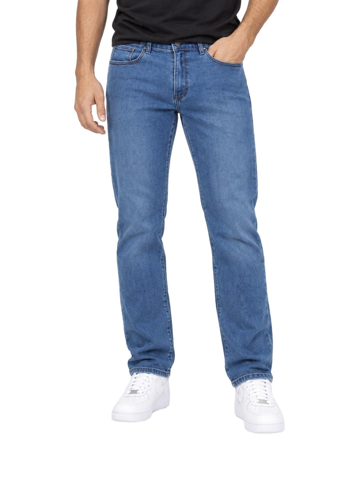 Hombre vistiendo jeans rectos de color azul stone con tenis blancos.