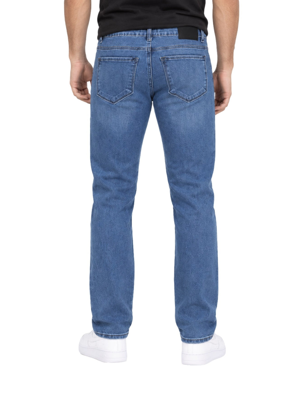 Hombre vistiendo jeans rectos de color azul stone con tenis blancos.