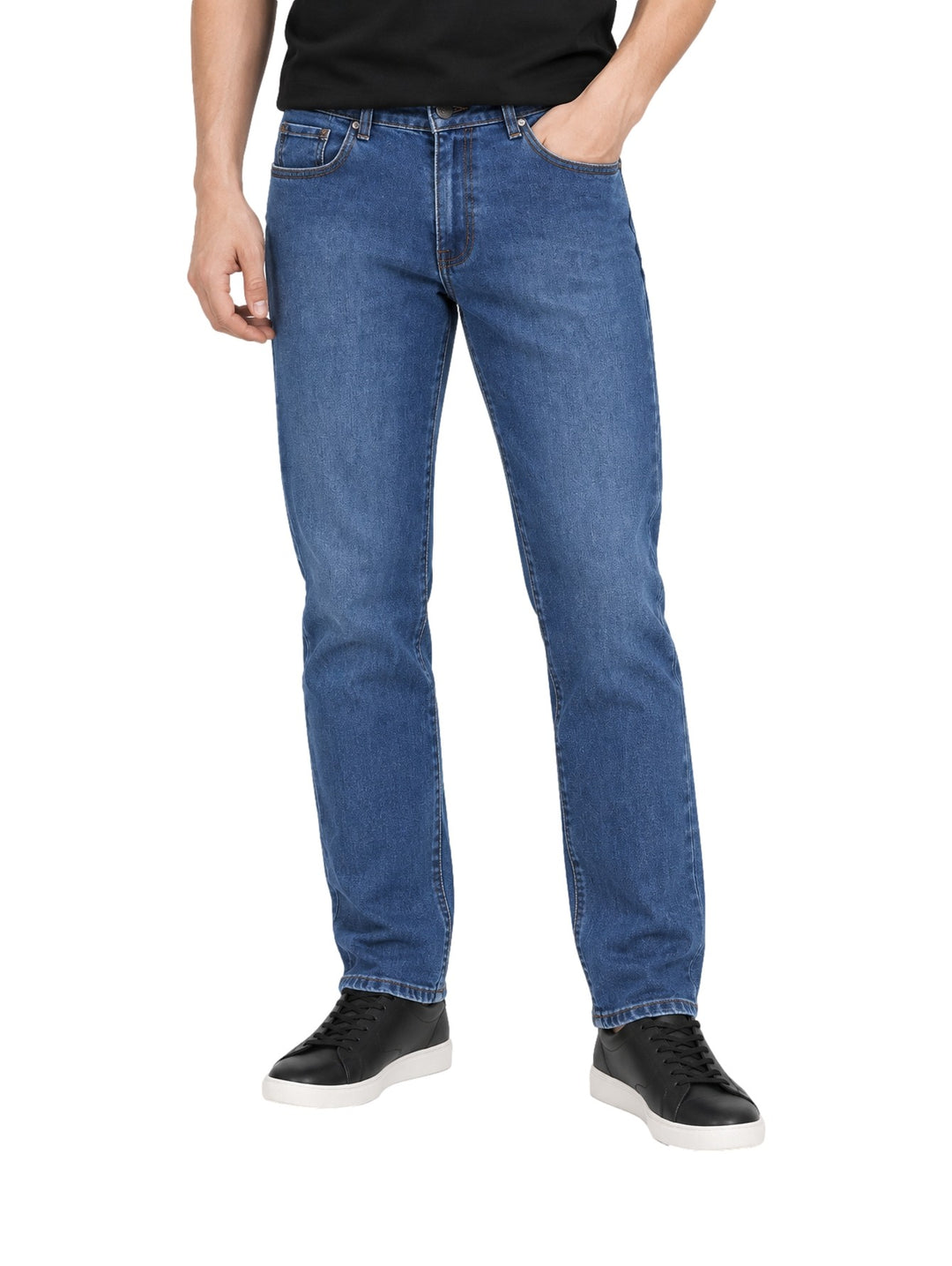 Hombre vistiendo jeans rectos de color azul stone con tenis negros sobre fondo blanco.