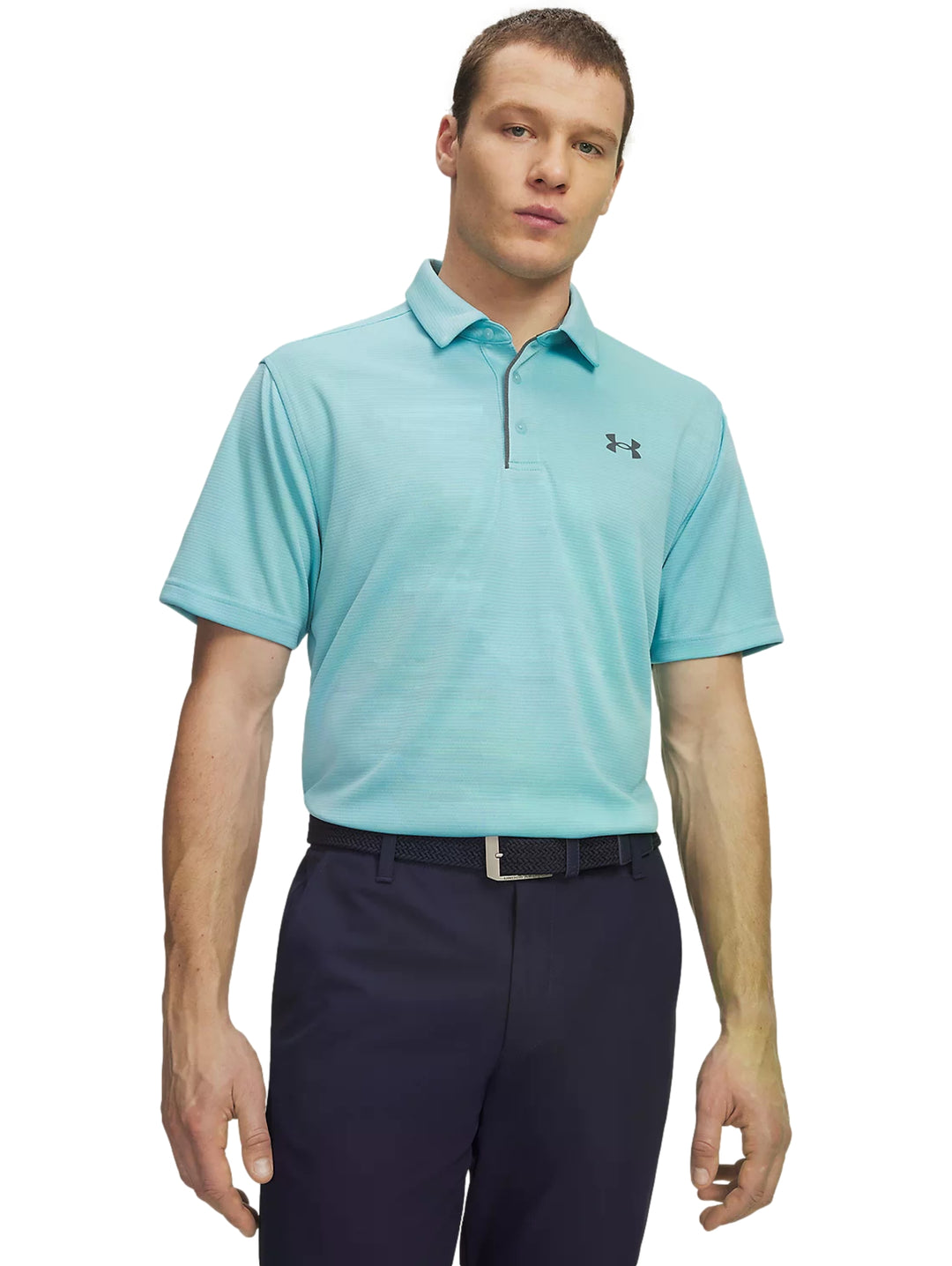 Hombre vistiendo playera polo Under Armour azul claro y pantalones azul marino.