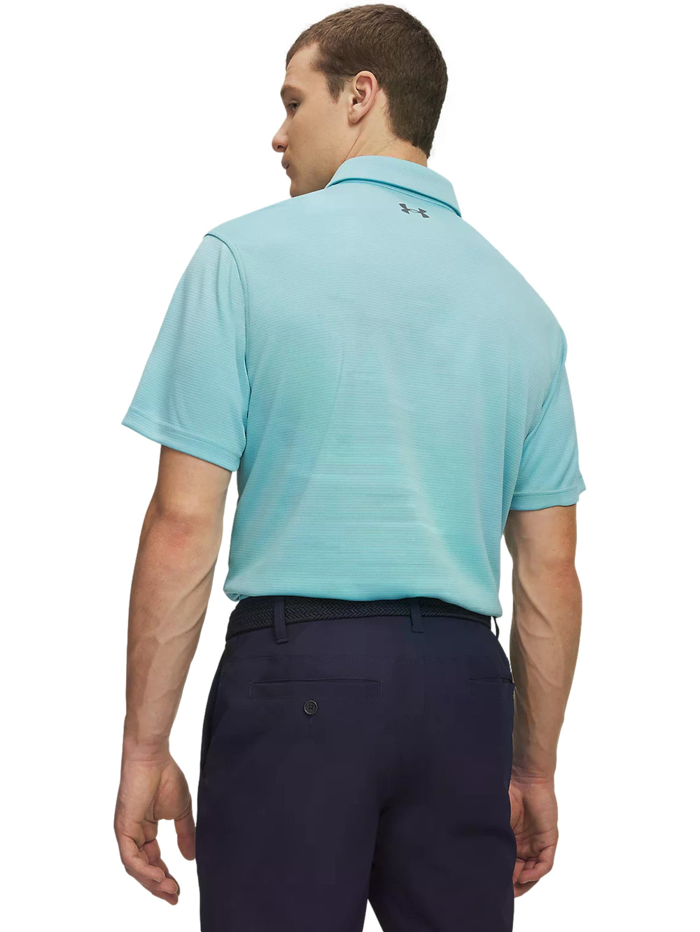 Hombre vistiendo playera polo Under Armour azul claro y pantalones azul marino.