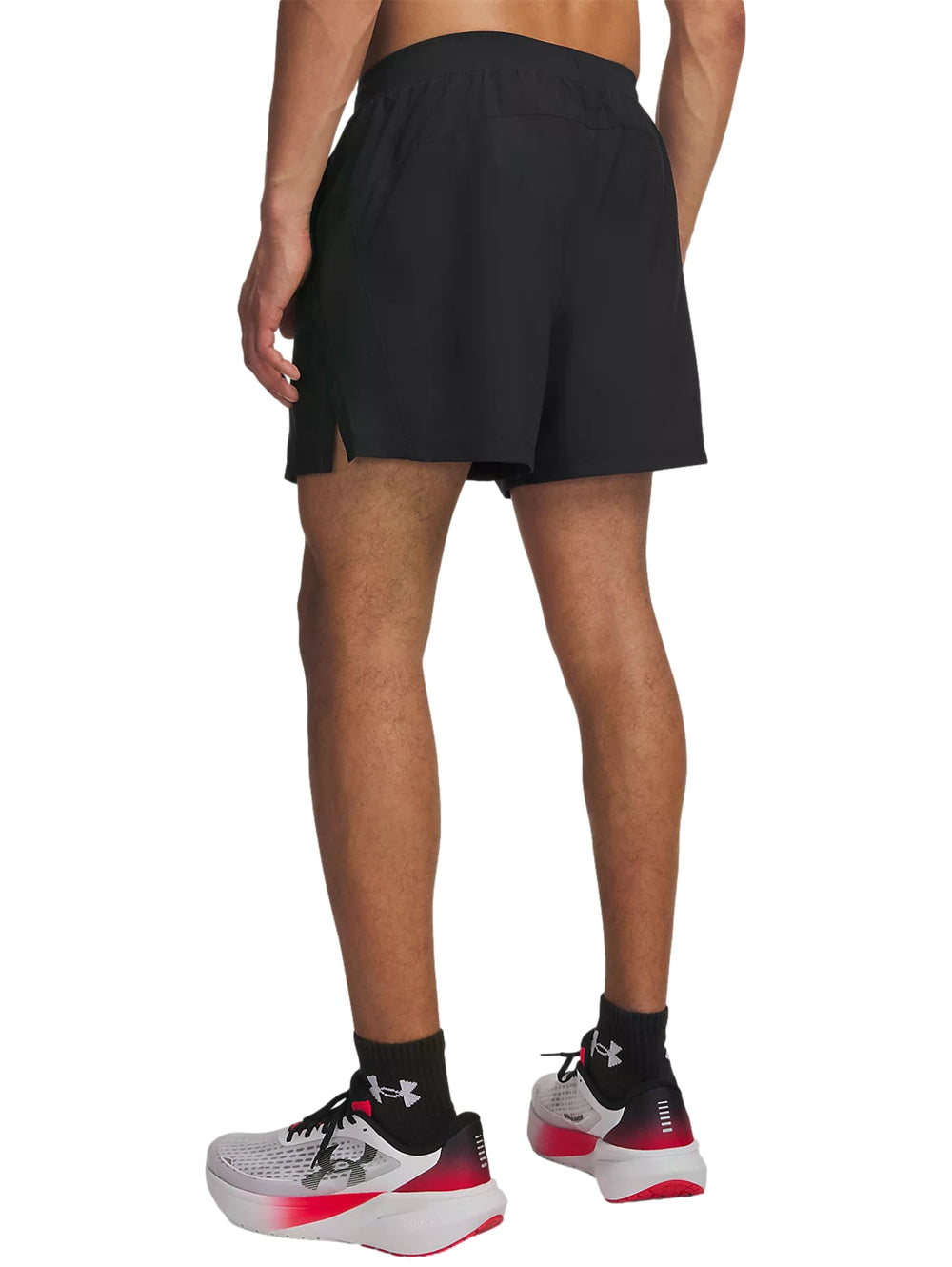 Hombre vistiendo shorts deportivos negros Under Armour, camiseta roja y calzado deportivo blanco con rojo.
