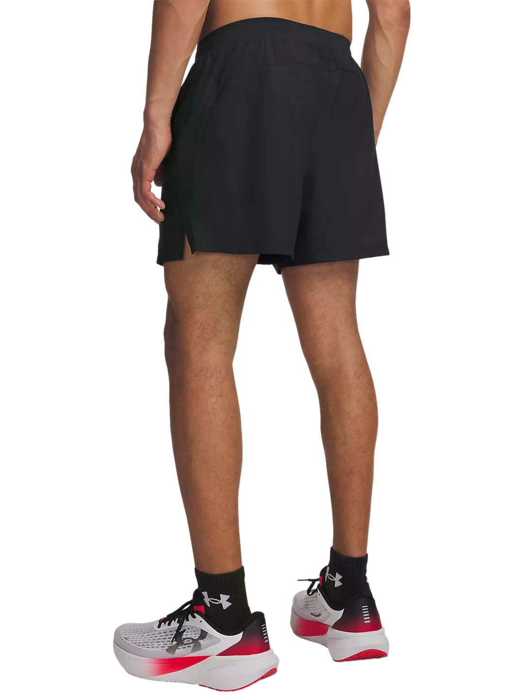 Hombre vistiendo shorts deportivos negros Under Armour, camiseta roja y calzado deportivo blanco con rojo.