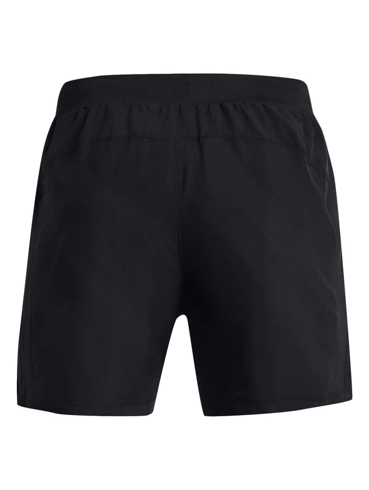 Hombre vistiendo shorts deportivos negros Under Armour, camiseta roja y calzado deportivo blanco con rojo.