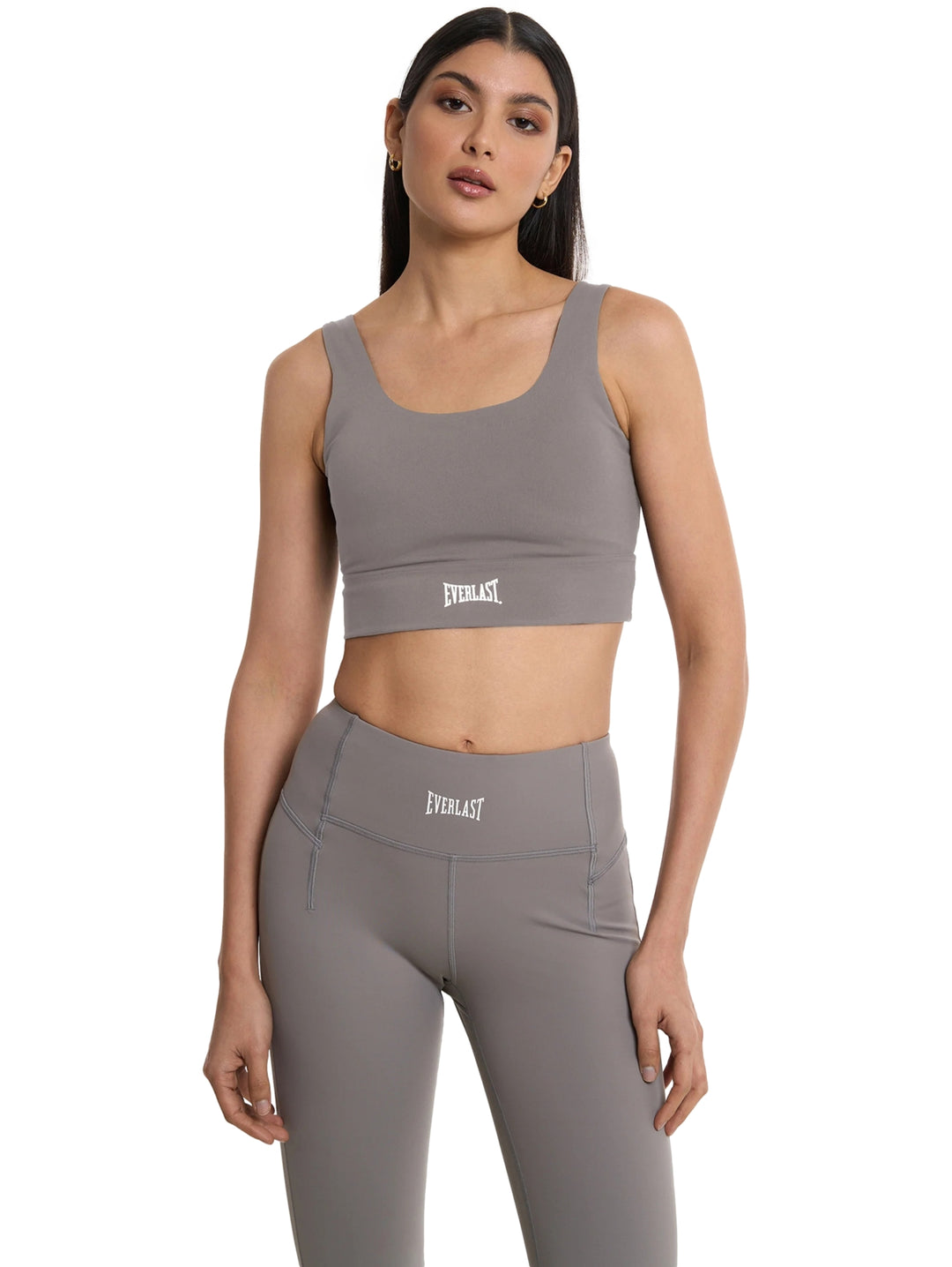 Mujer vistiendo un top corto y leggings deportivos de color gris de la marca Everlast.