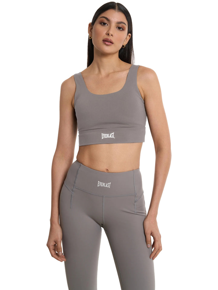 Mujer vistiendo un top corto y leggings deportivos de color gris de la marca Everlast.