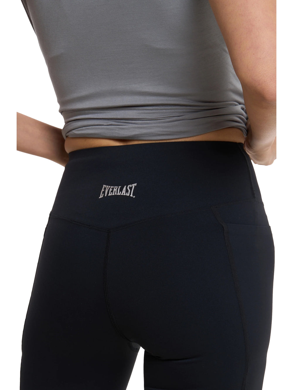 Mujer vistiendo short deportivo ajustado color negro y tenis blancos.