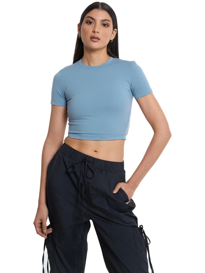 Mujer vistiendo playera crop top deportiva color azul de la marca Everlast.