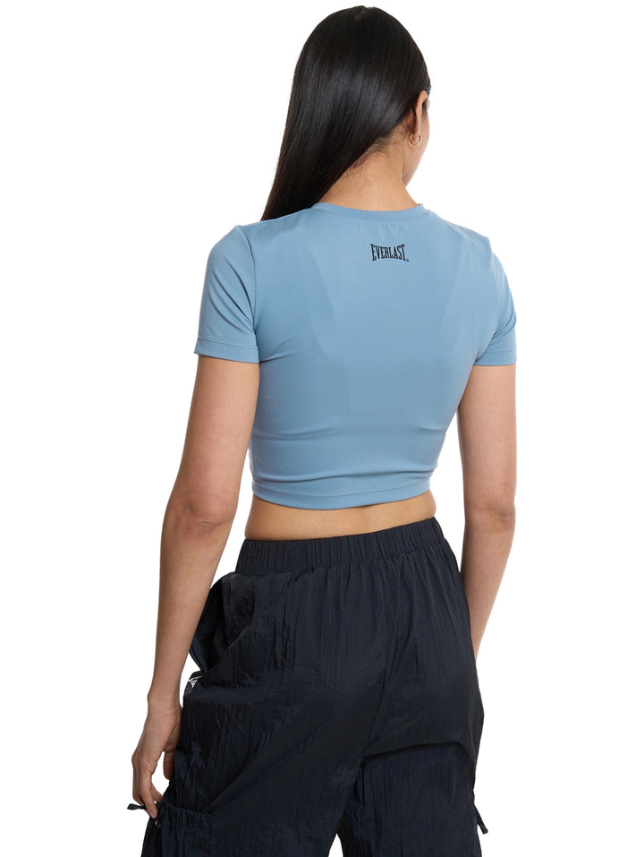 Mujer vistiendo playera crop top deportiva color azul de la marca Everlast.