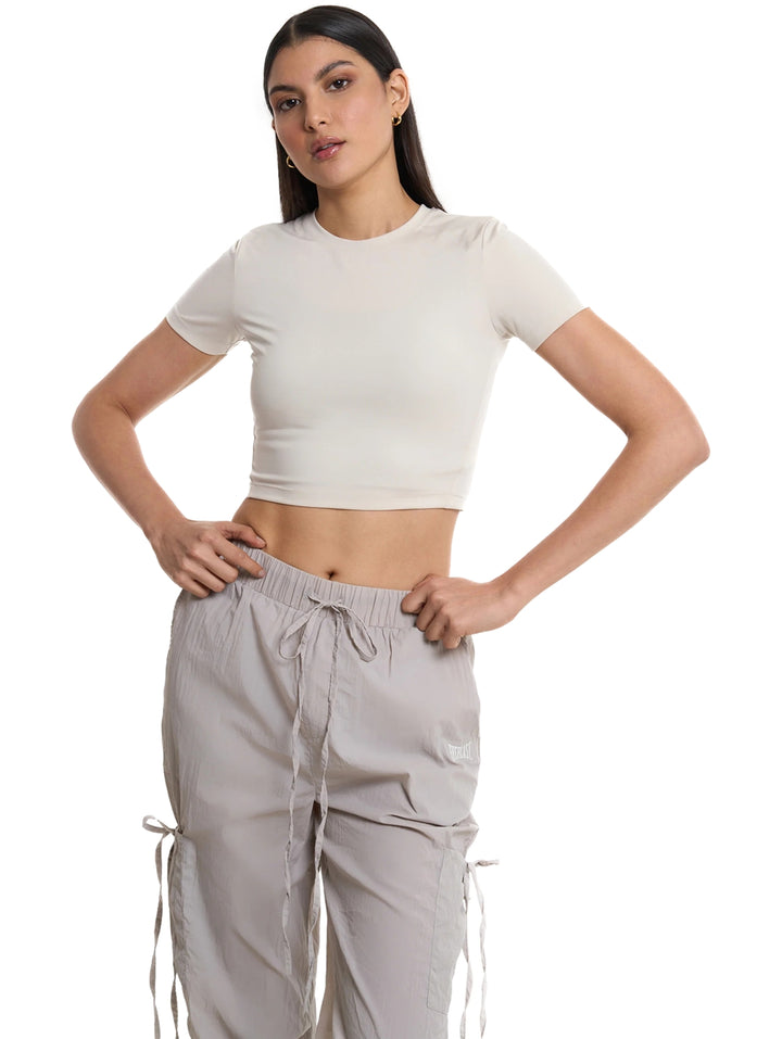 Mujer vistiendo playera corta gris claro de cuello redondo y manga corta.