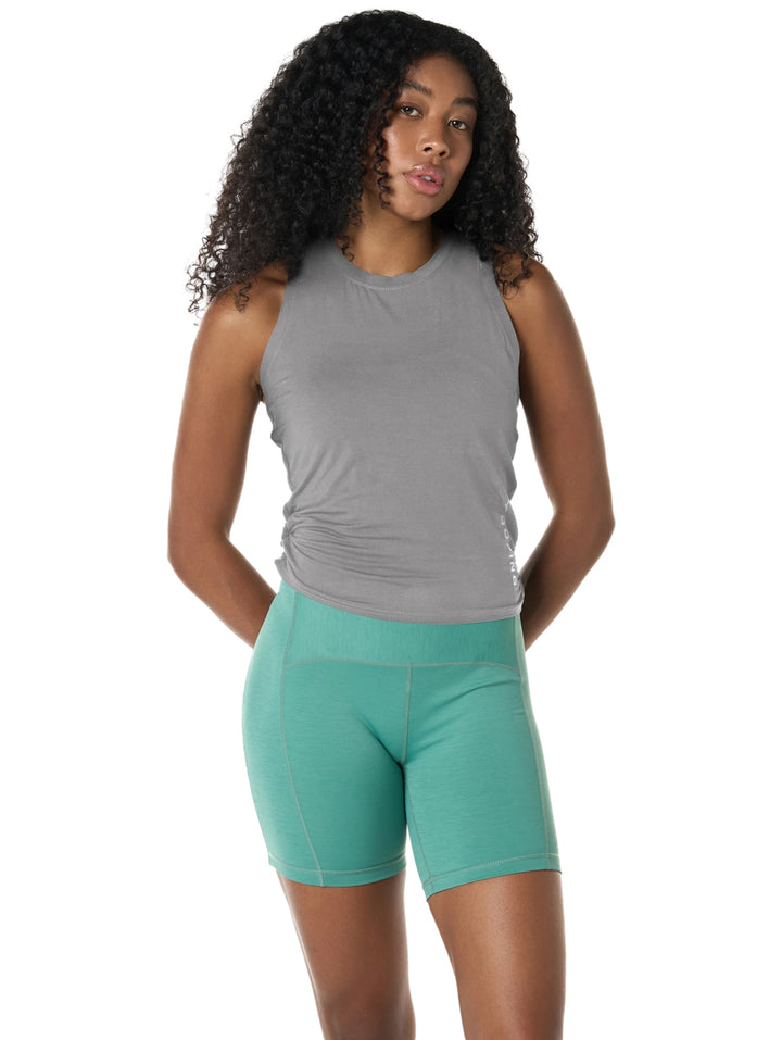 Mujer vistiendo playera gris sin mangas y shorts deportivos color verde.