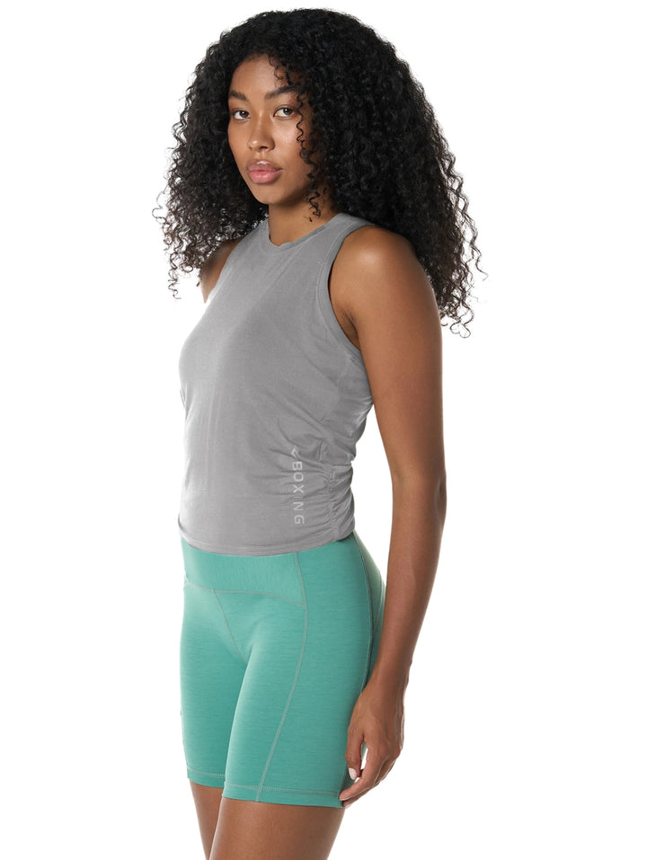 Mujer vistiendo playera gris sin mangas y shorts deportivos color verde.