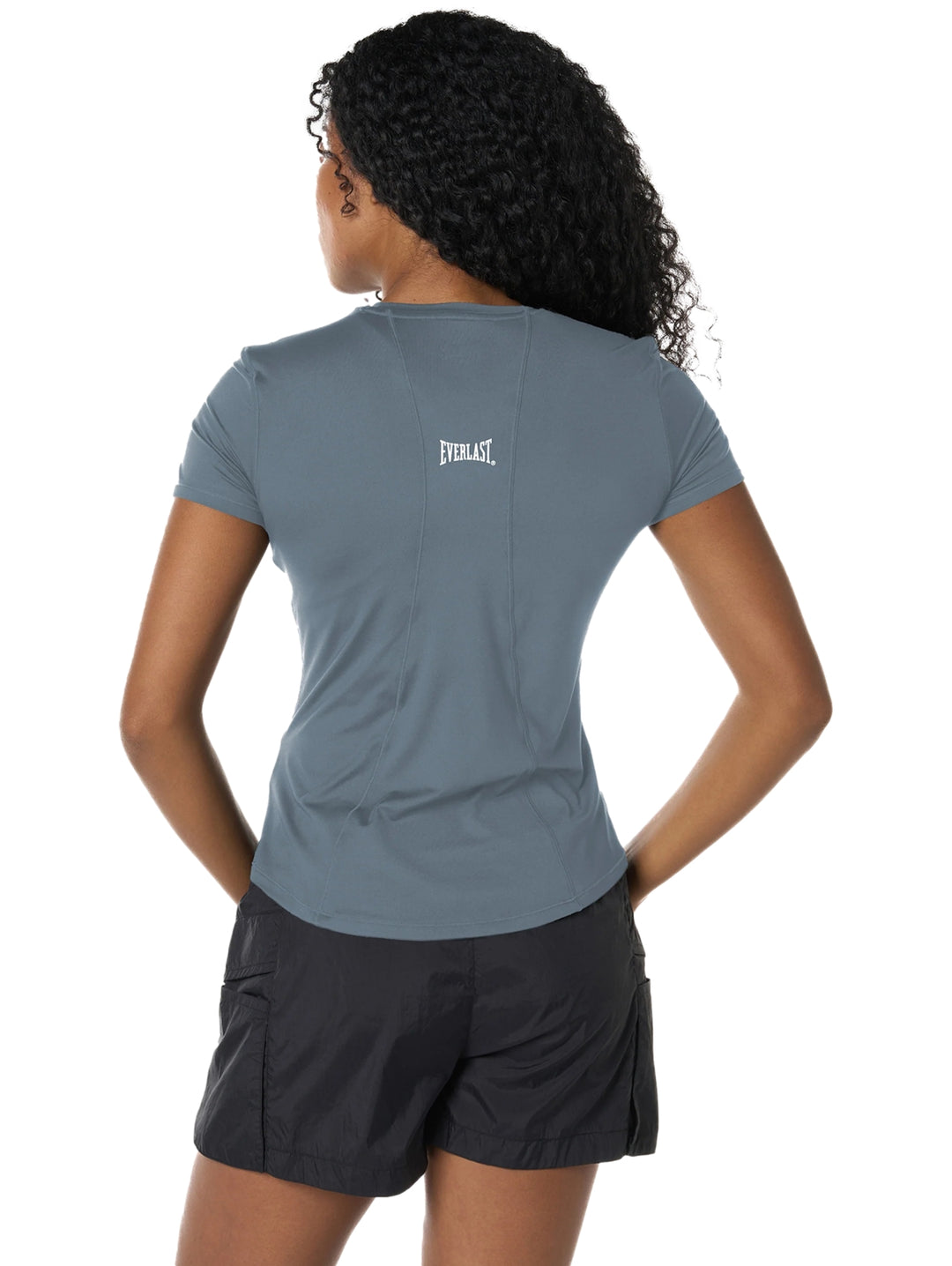 Mujer vistiendo playera deportiva azul de manga corta y shorts negros sobre fondo blanco.