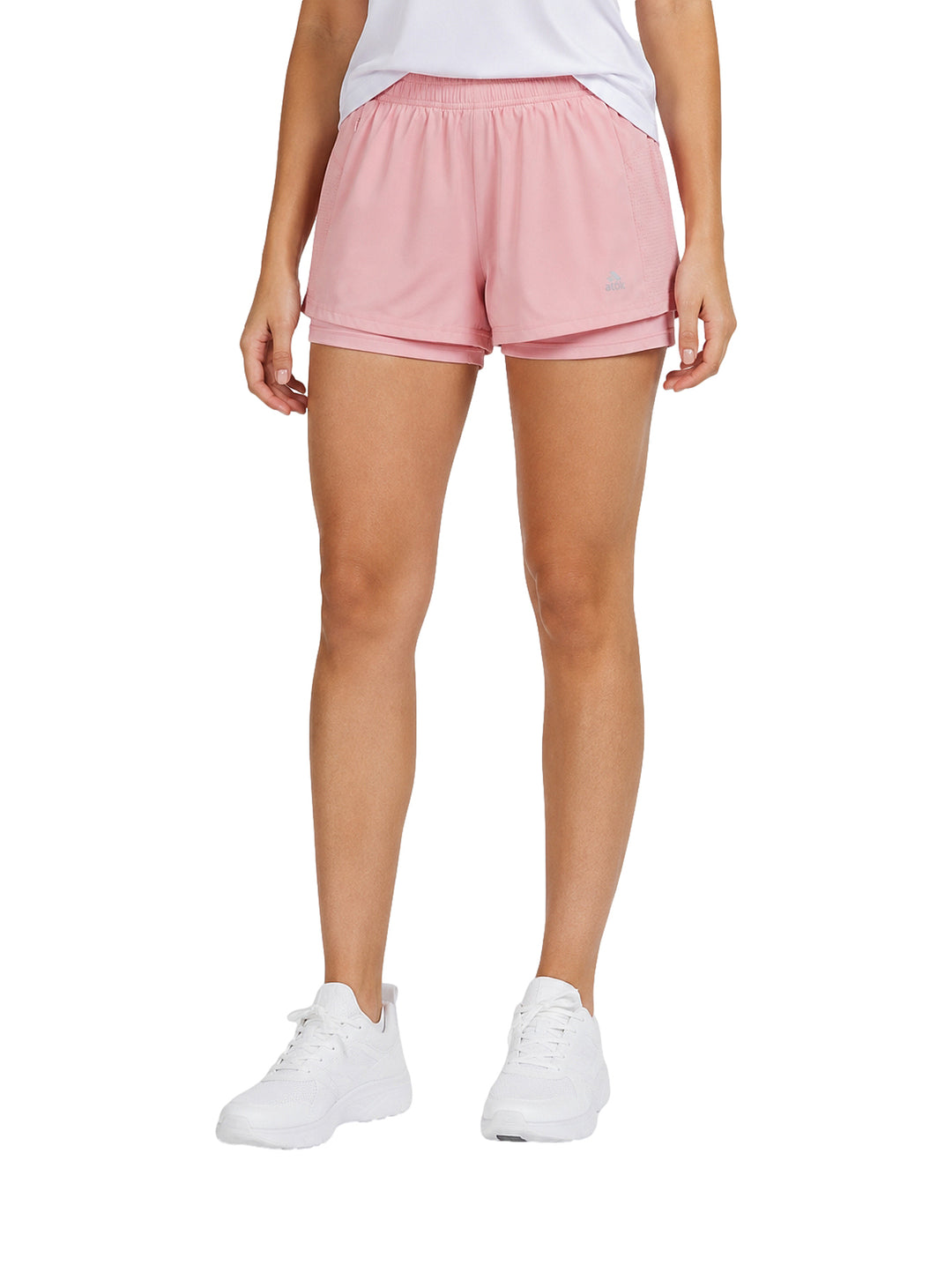Mujer vistiendo shorts deportivos de color rosa claro y tenis blancos.