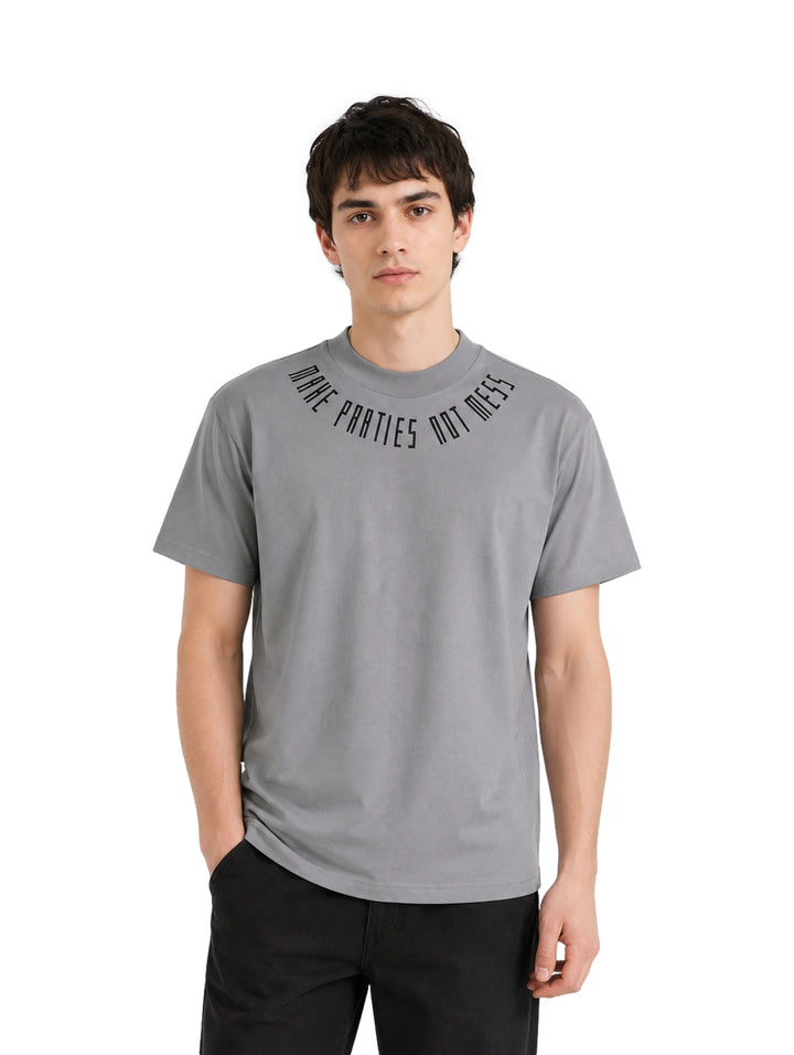 Hombre usando playera gris de manga corta con texto en el cuello.