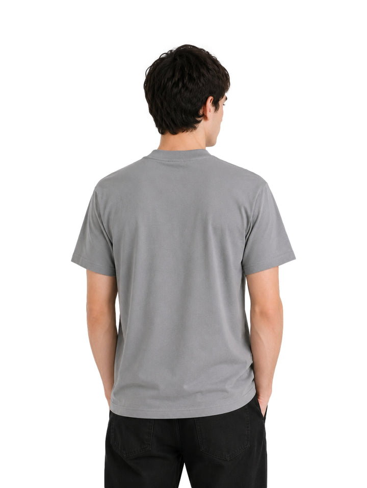 Hombre usando playera gris de manga corta con texto en el cuello.
