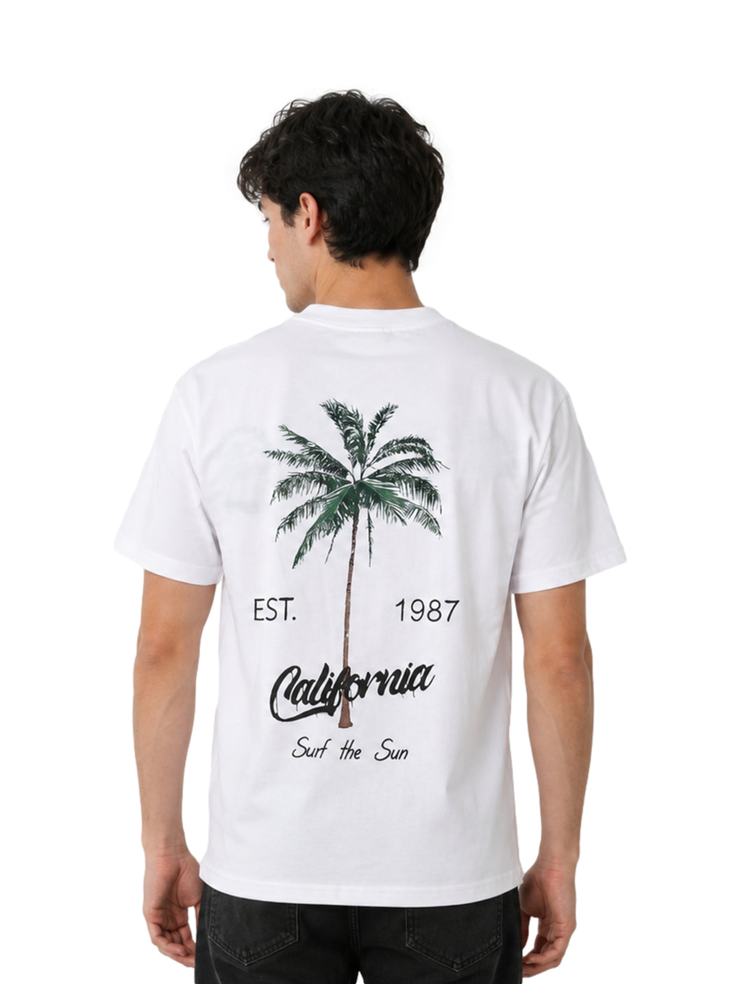 Hombre vistiendo playera blanca de manga corta con estampado pequeño en el pecho.