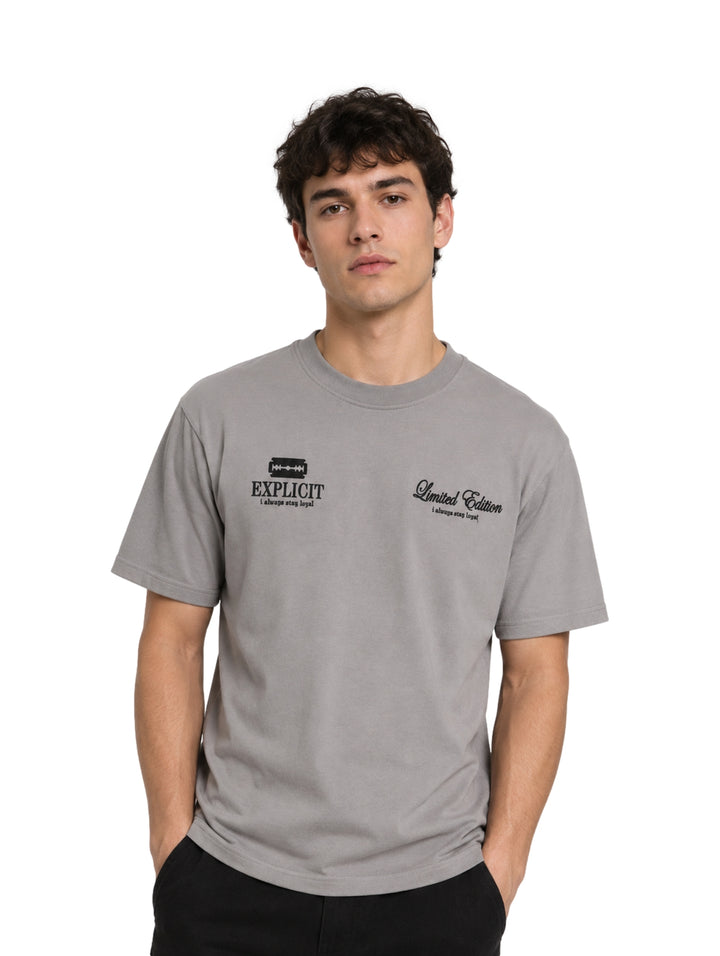 Hombre vistiendo una playera de color gris con estampados negros en el pecho.