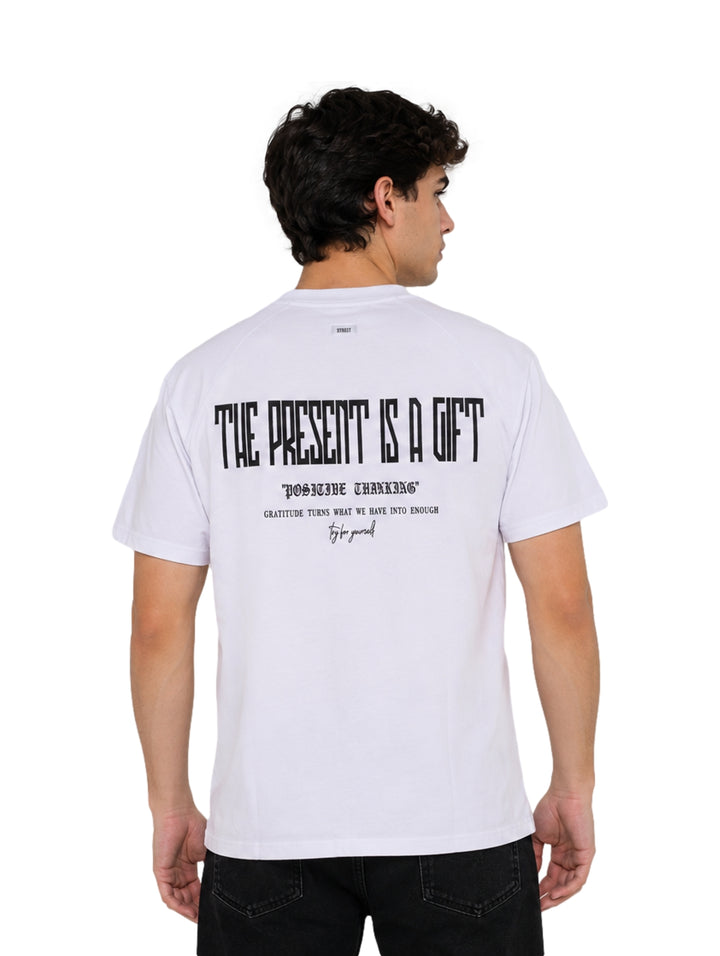 Hombre vistiendo playera blanca de manga corta con estampado pequeño en el pecho.