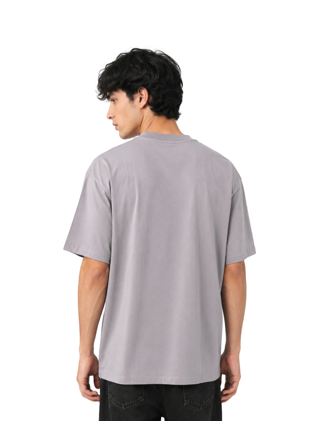 Hombre vistiendo playera color gris de corte amplio con estampado gráfico negro en el pecho.