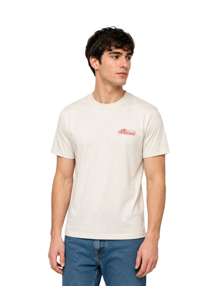 Hombre vistiendo una playera de manga corta color arena con cuello redondo y un pequeño logo rojo en el pecho.