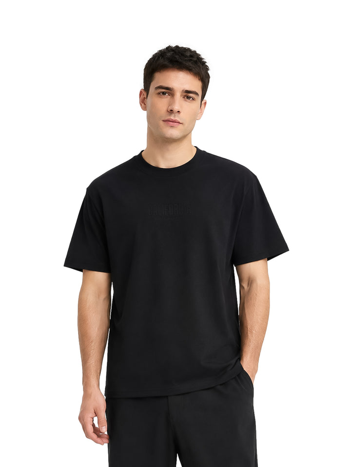 Hombre vistiendo una playera de manga corta color negro sobre fondo blanco.