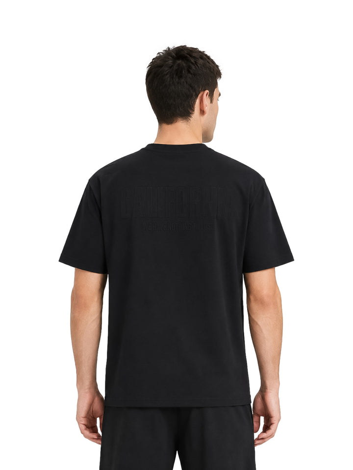 Hombre vistiendo una playera de manga corta color negro sobre fondo blanco.