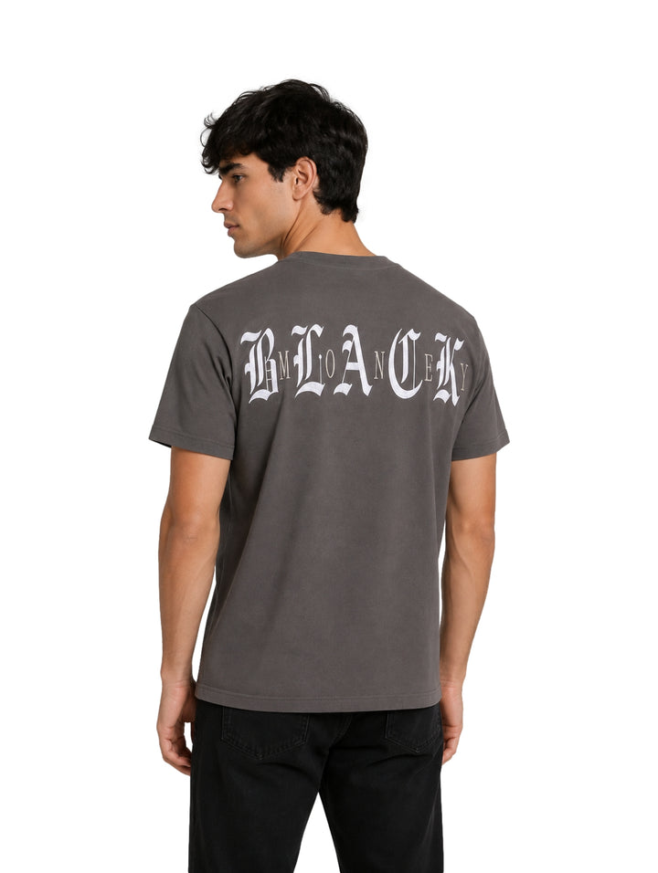 Hombre vistiendo una playera de manga corta color gris oscuro con un pequeño texto blanco en el pecho.