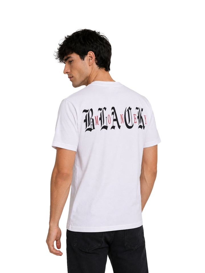 Hombre vistiendo una playera blanca de manga corta con un pequeño logo en el pecho y pantalones negros.