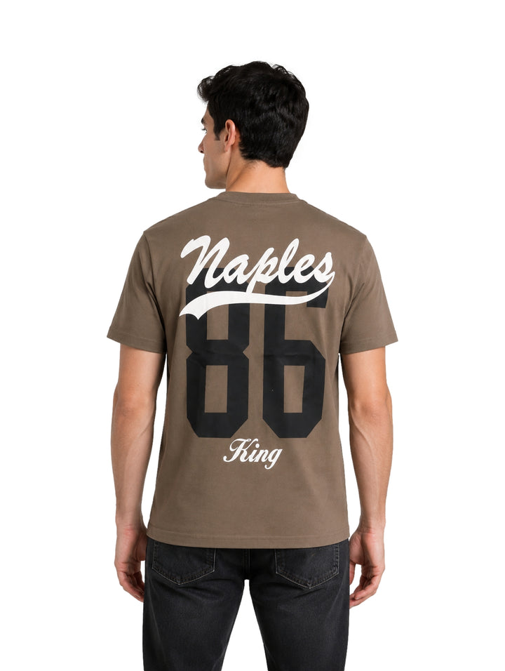 Hombre vistiendo una playera de color verde militar con el texto Naples en el pecho.