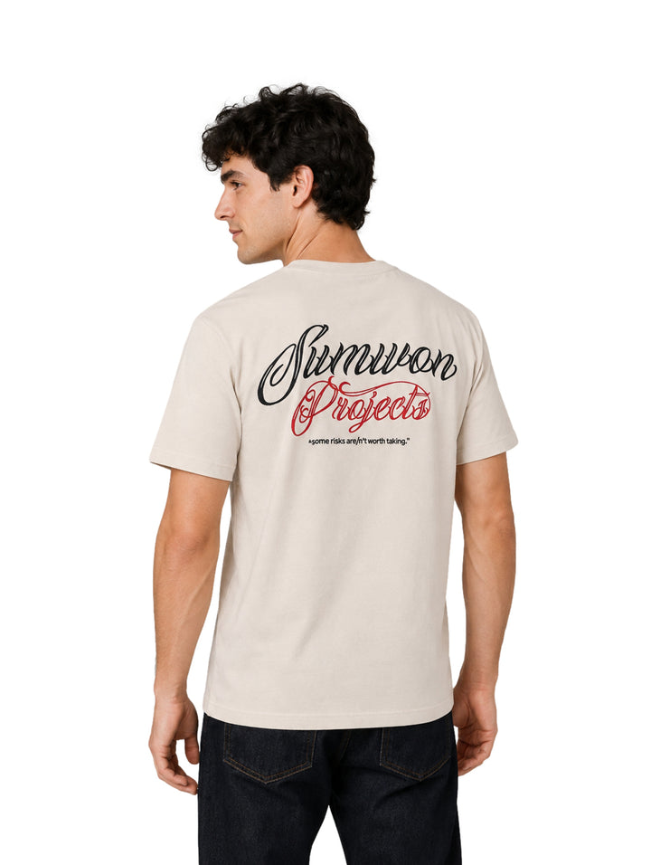 Hombre vistiendo una playera de manga corta color beige con un pequeño logotipo en el pecho.