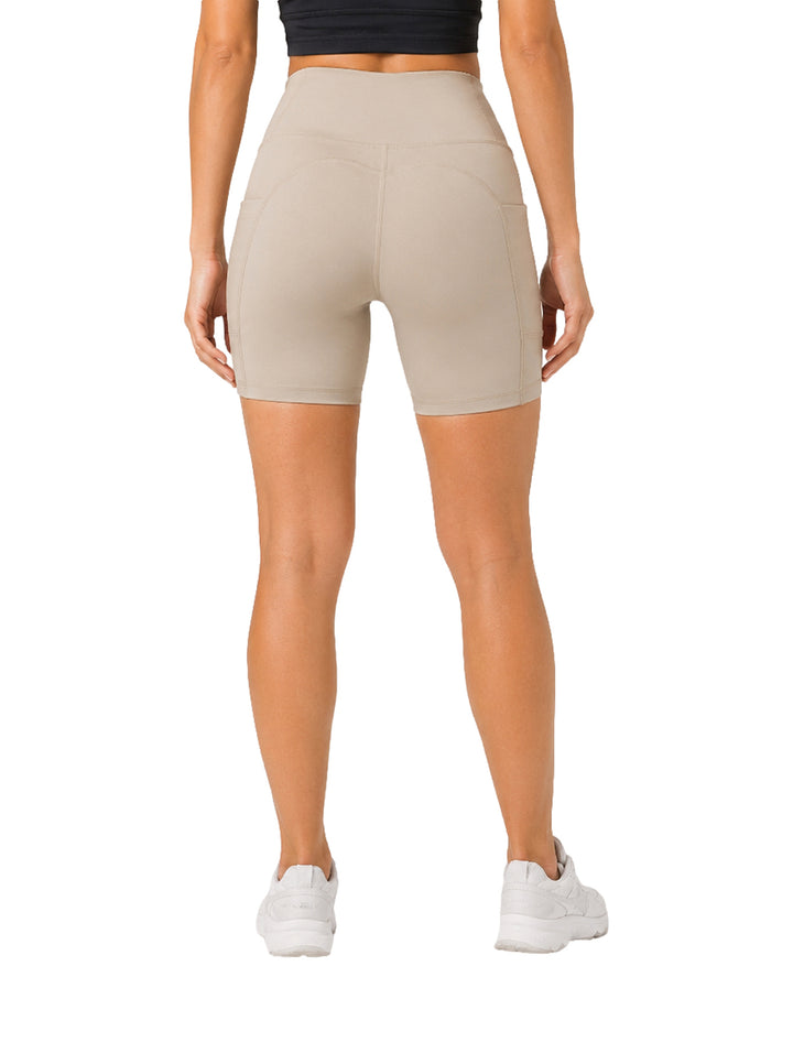 Mujer vistiendo shorts deportivos ajustados de color arena marca Atok Performance.