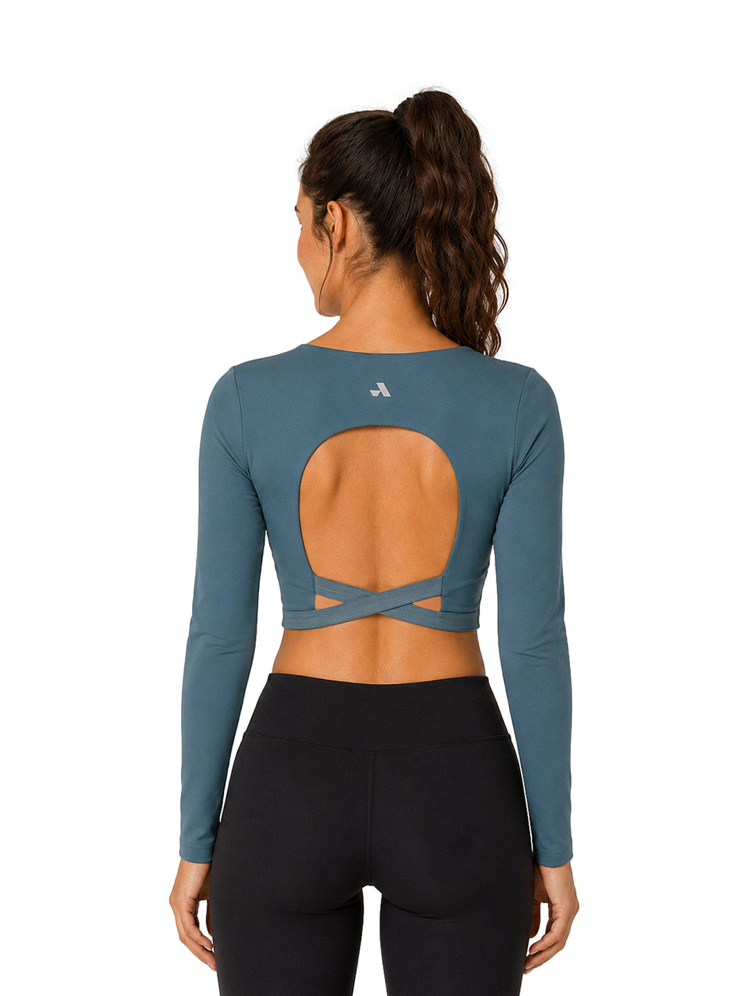 Mujer vistiendo un top corto de manga larga color azul y leggings negros.