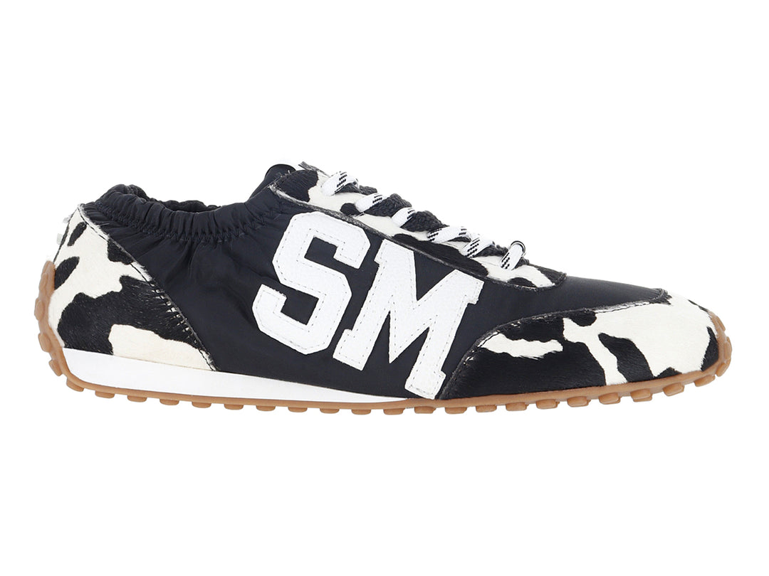Tenis Steve Madden negros y blancos con estampado de vaca y letras SM blancas en el costado.