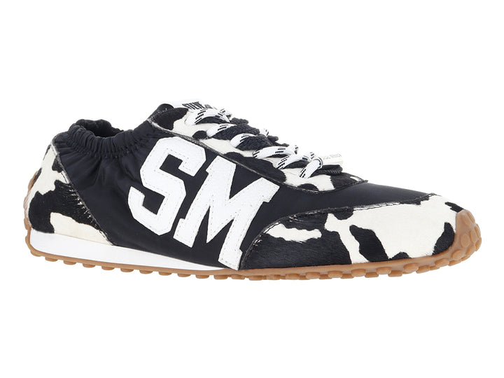 Tenis Steve Madden negros y blancos con estampado de vaca y letras SM blancas en el costado.
