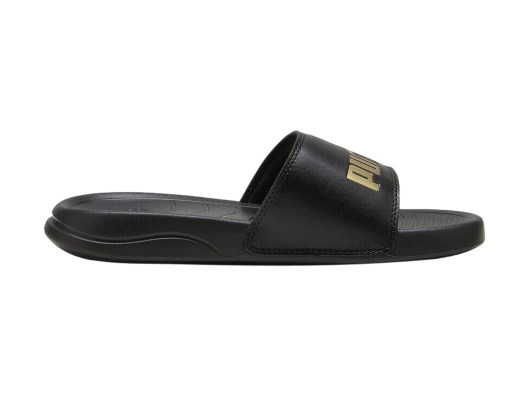 Sandalia PUMA Popcat 20 de color negro con logotipo dorado en la correa superior.