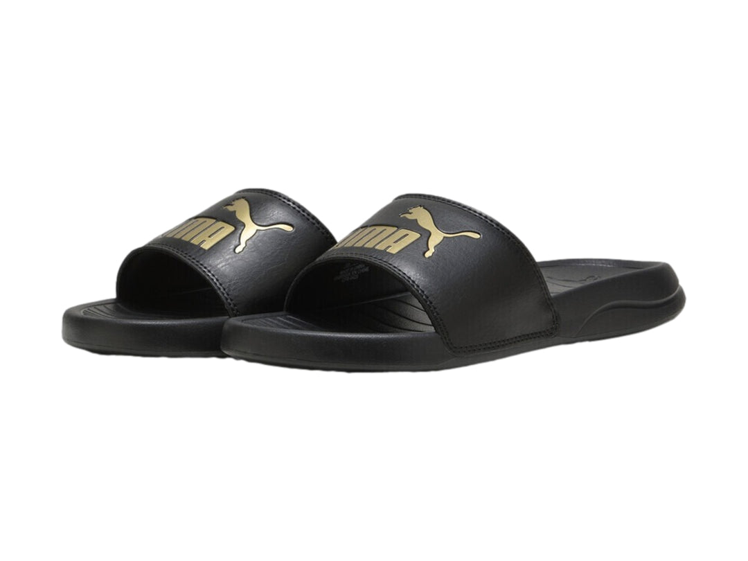 Sandalia PUMA Popcat 20 de color negro con logotipo dorado en la correa superior.