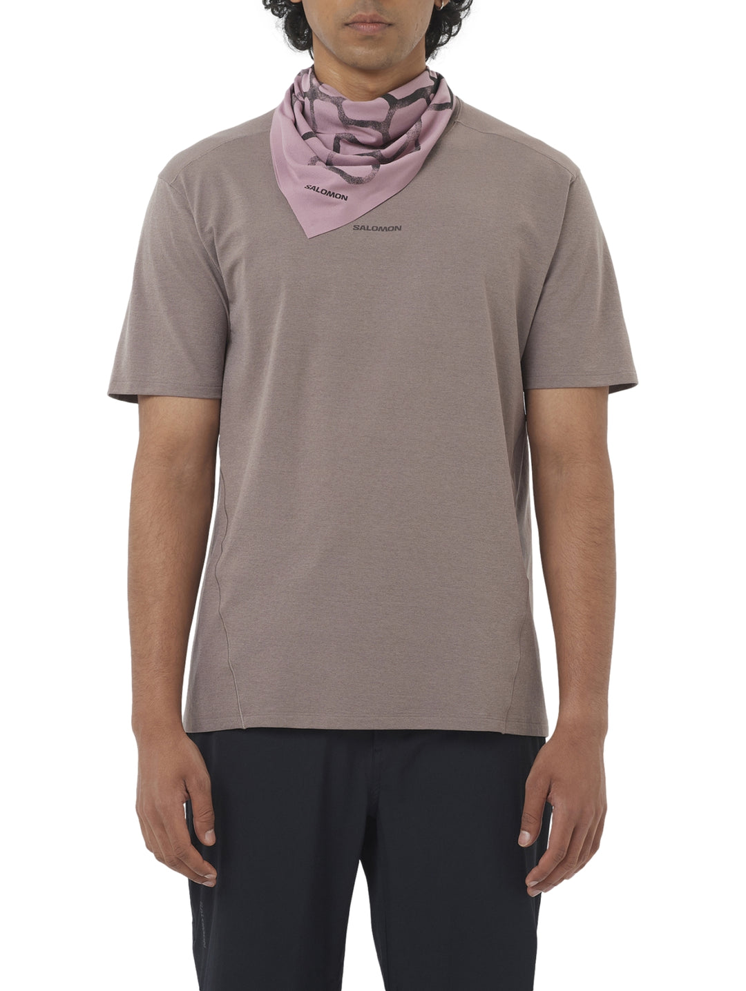 Hombre vistiendo playera deportiva Salomon de color café con manga corta.