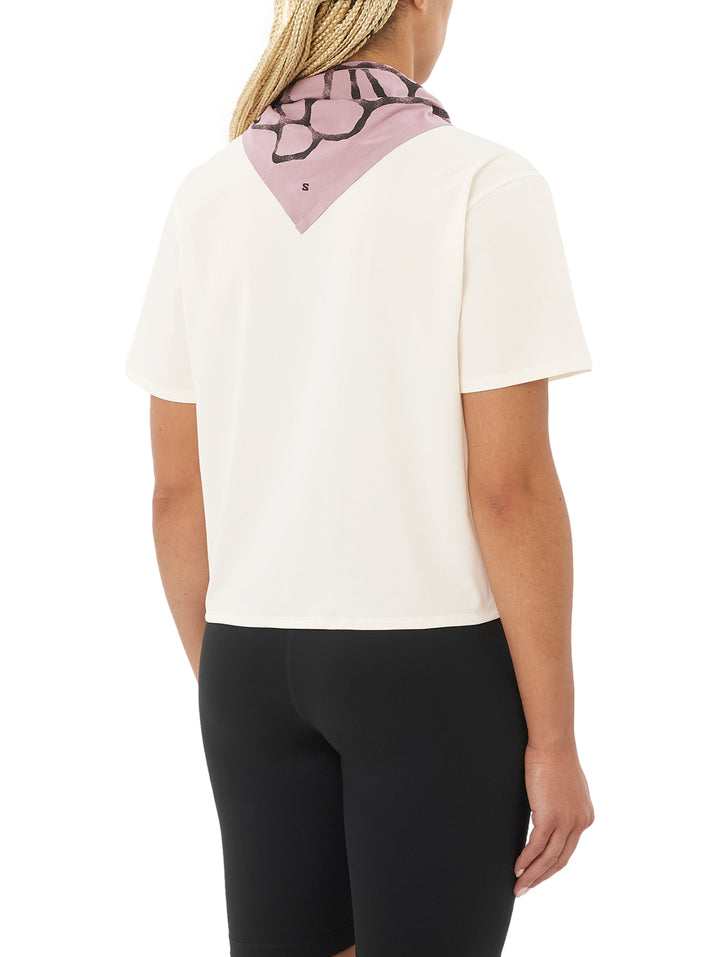 Mujer usando playera deportiva Salomon color beige y pantalones negros.