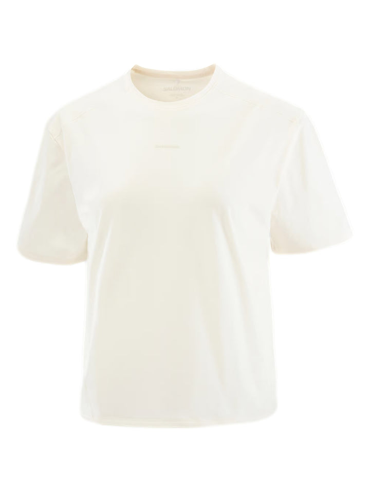 Mujer usando playera deportiva Salomon color beige y pantalones negros.