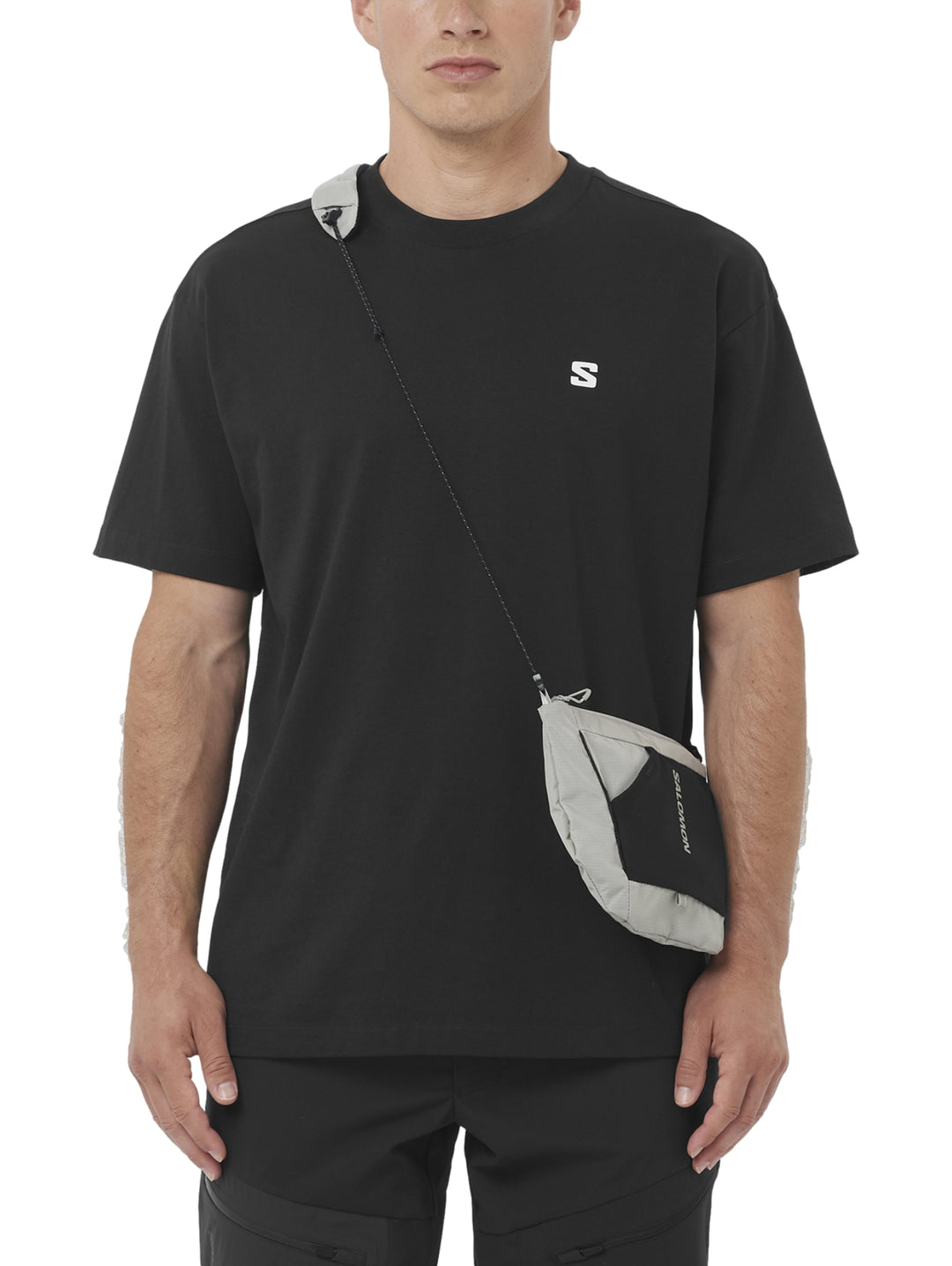 Hombre vistiendo playera deportiva negra de manga corta con logotipo pequeño de Salomon en el pecho.