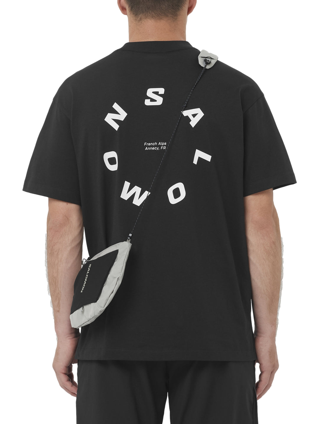 Hombre vistiendo playera deportiva negra de manga corta con logotipo pequeño de Salomon en el pecho.