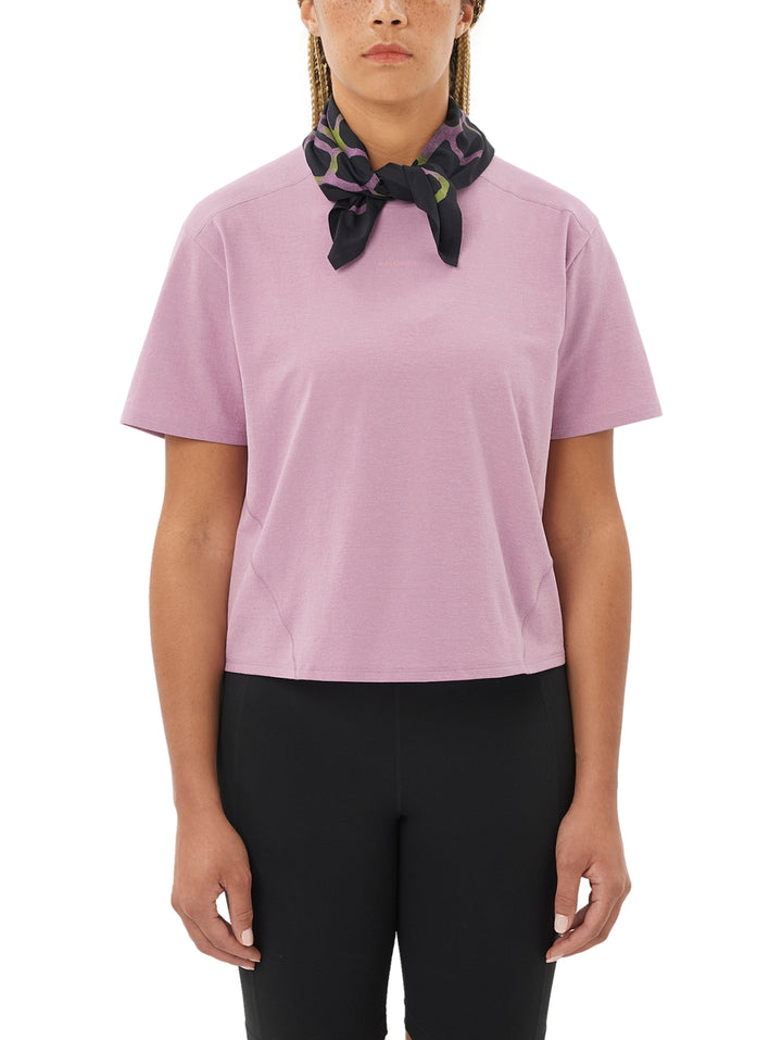 Mujer vistiendo playera deportiva color rosa de manga corta y leggings negros.