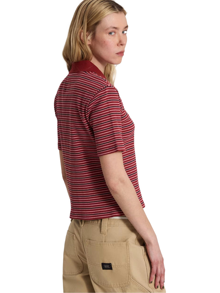 Mujer vistiendo playera polo VANS a rayas horizontales rojas y negras con cuello y manga corta.