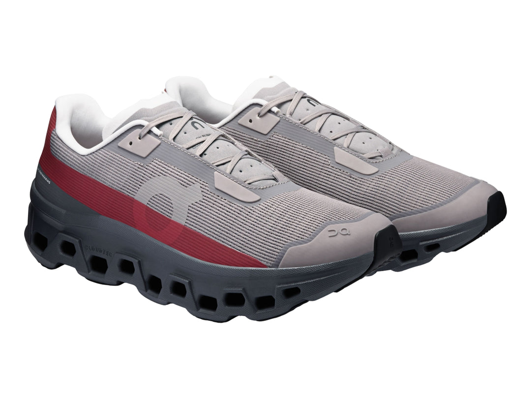Tenis On Cloud Cloudmonster Void Eclipse para hombre en color gris con franja roja y suela oscura.