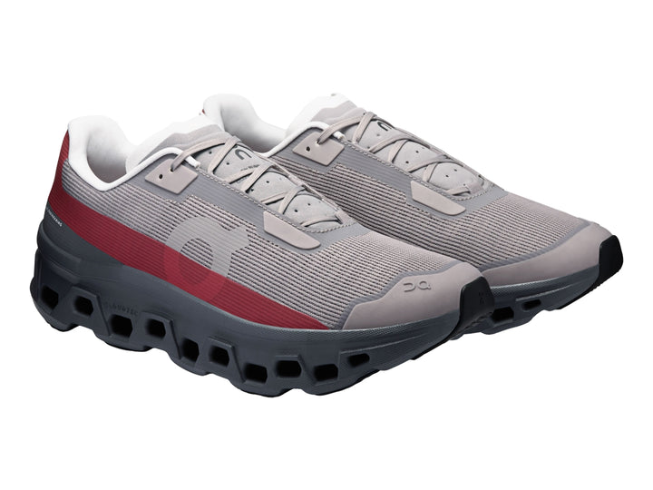 Tenis On Cloud Cloudmonster Void Eclipse para hombre en color gris con franja roja y suela oscura.